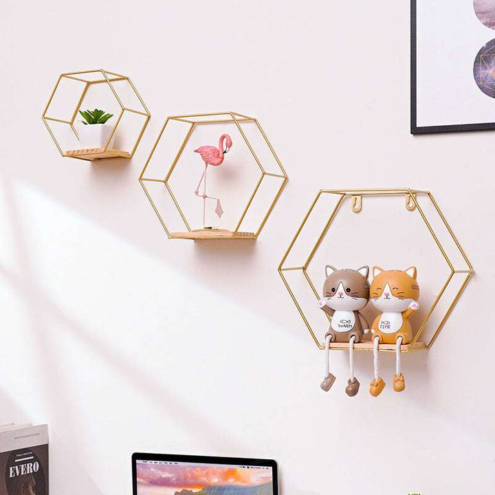 VibeCore Hexagonal Floating Wall Shelves in gold, displayed on a wall in three sizes, showcasing a mix of decorative items like plants and frames.