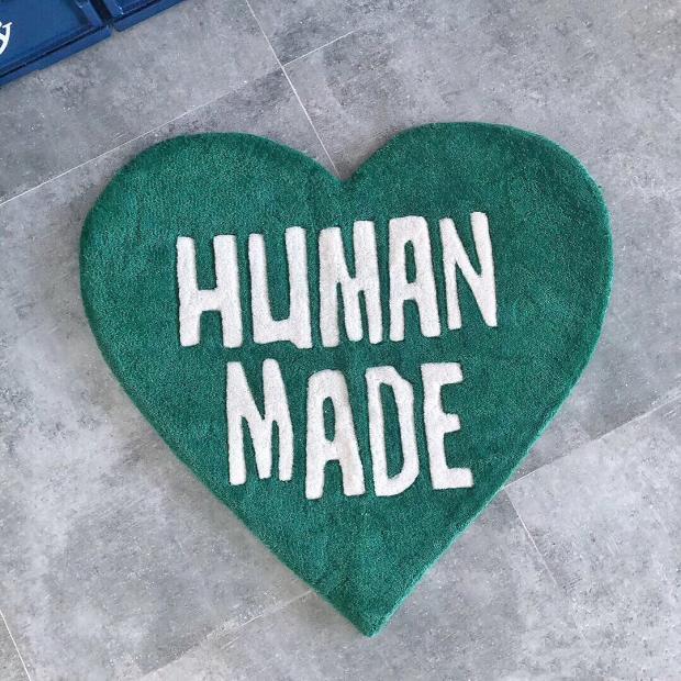 VibeCore Human Made Accent Rug in green, placed on the floor with its heart-shaped design clearly visible. The vibrant color and modern message stand out, while the non-slip backing ensures safety and comfort in any space.