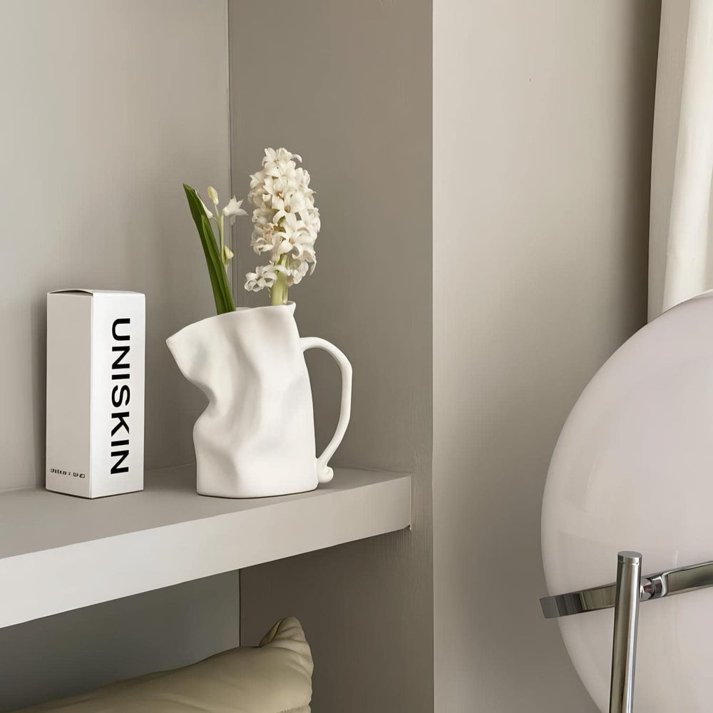 VibeCore Irregularly Folded Ceramic Vase in White with Dried Flowers, showcasing a sculptural minimalist design on a modern shelf.
