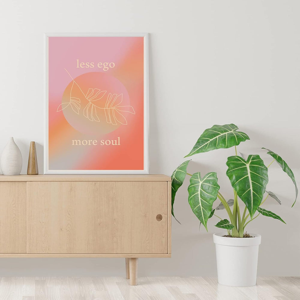 VibeCore Less Ego More Soul canvas print framed against a wall on TV table, minimalist inspirational typography art for modern bedroom, dorm, or apartment decor.