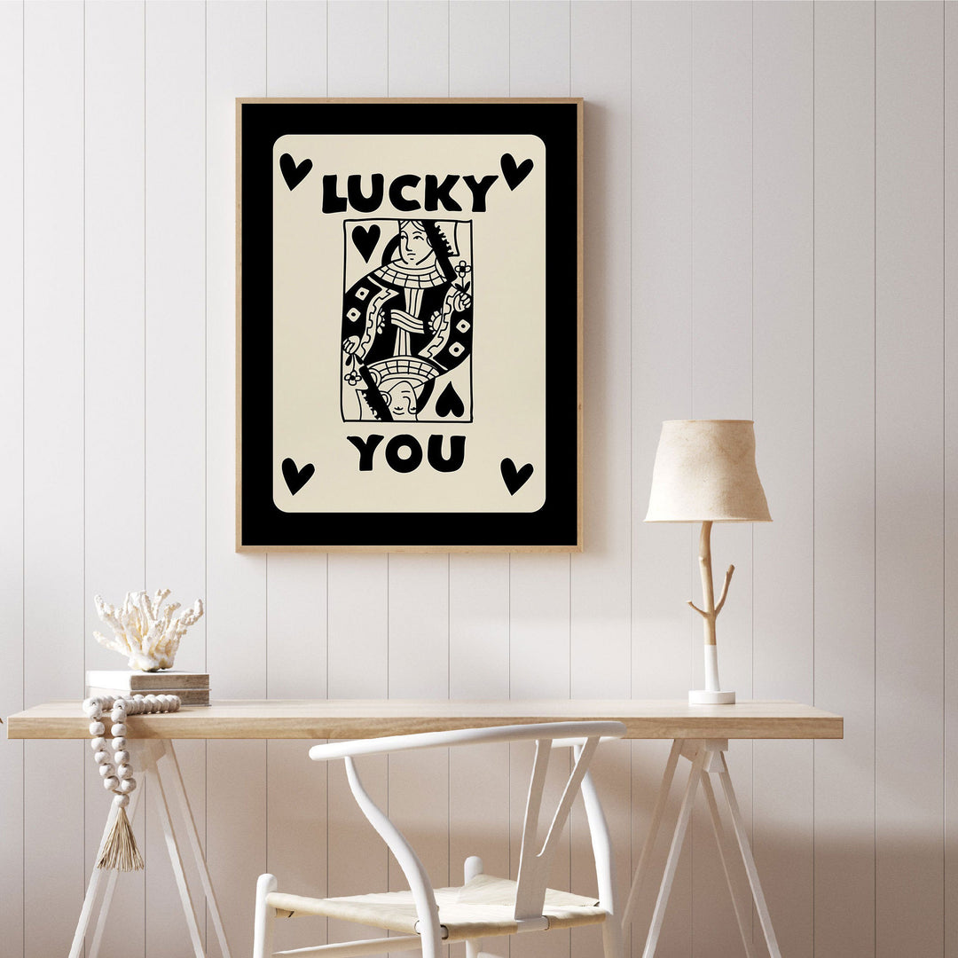 A bold 'Lucky You Queen' playing card-inspired canvas poster on a wall, featuring striking black and gold details and a playful queen design, adding a vintage yet modern touch to any space.