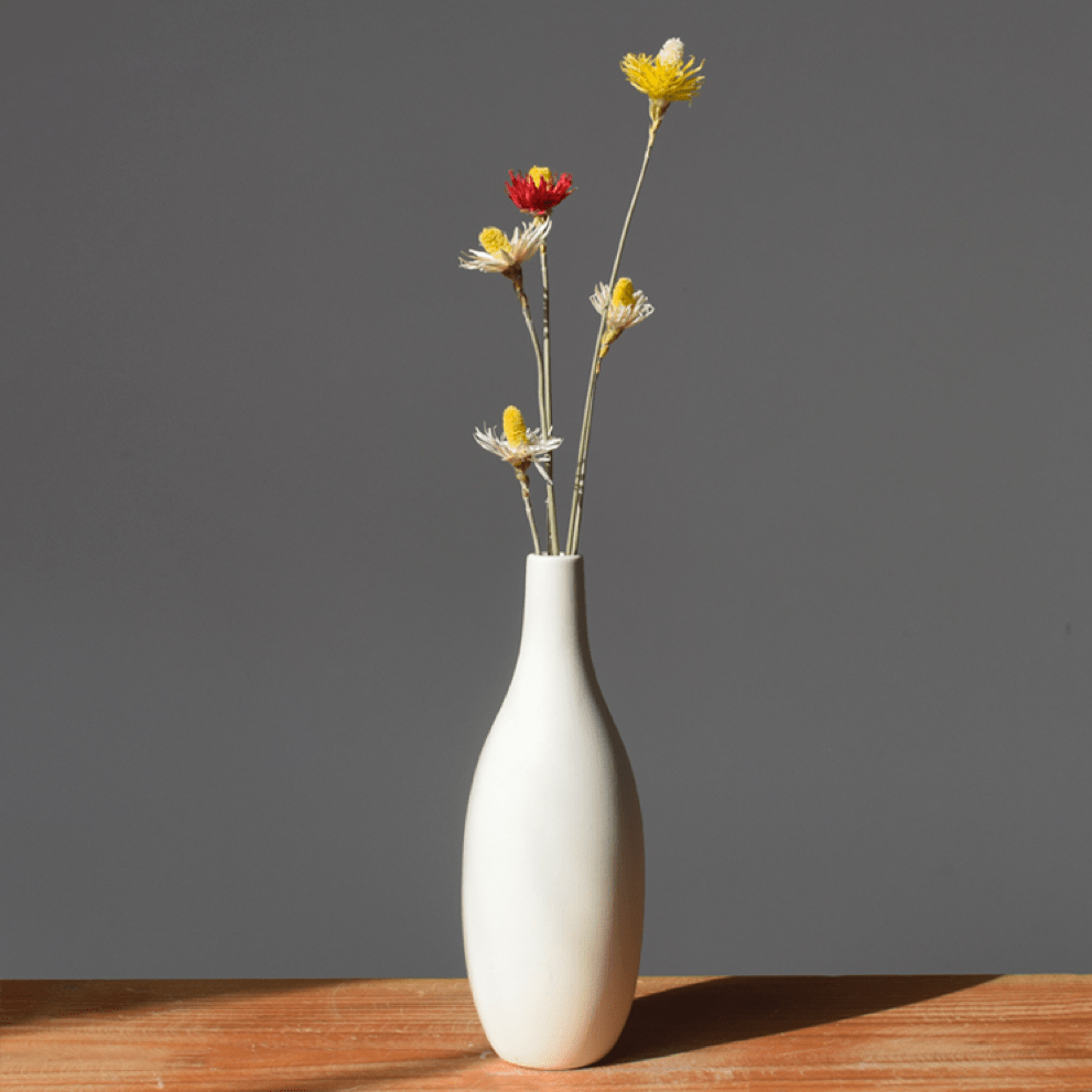 VibeCore Matte White Ceramic Flower Vase with fake flowers on wooden table, featuring a minimalist tube design, perfect for adding a modern touch and enhancing any room decor with faux floral arrangements.