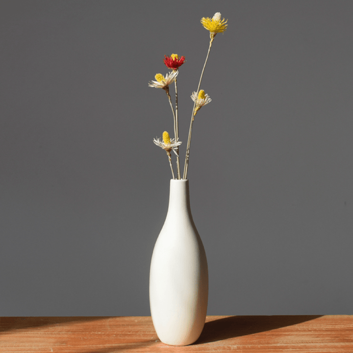VibeCore Matte White Ceramic Flower Vase with fake flowers on wooden table, featuring a minimalist tube design, perfect for adding a modern touch and enhancing any room decor with faux floral arrangements.