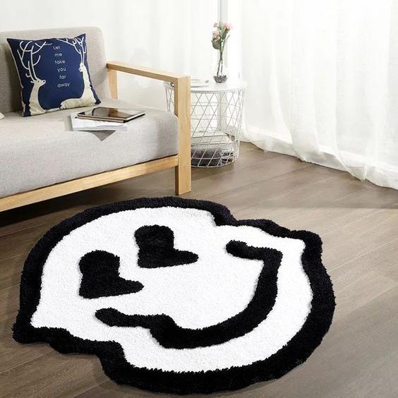 VibeCore Melting Smiley Accent Rug White In Living Room, placed on the floor in front of a couch, creating a vibrant, playful atmosphere with its cheerful design and soft texture that adds both comfort and a fun, artistic vibe to the space.