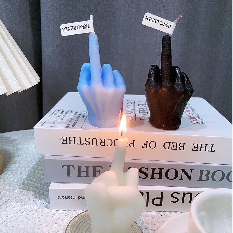 VibeCore Middle Finger Candle in black, white, and blue colors, placed on a book.
