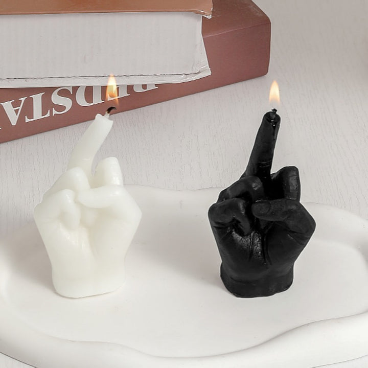Black and white eco-friendly soy wax candles shaped like middle fingers with sleek cylindrical bases.