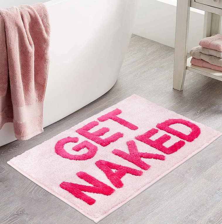 Aesthetic "Pink Get Naked Bath Mat" displayed in front of another tub, featuring a vibrant pink color and playful design. The soft, plush texture adds comfort and warmth to your bathroom, with a non-slip backing for safety and stability, making it a fun and functional addition to your space.