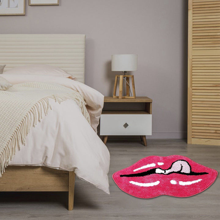 The VibeCore Pink Lips Tongue Out Accent Rug in a bedroom, featuring a vibrant pink lip and tongue design. The playful rug adds a pop of color and a cozy touch, enhancing the room's aesthetic while offering comfort and safety with its non-slip backing.