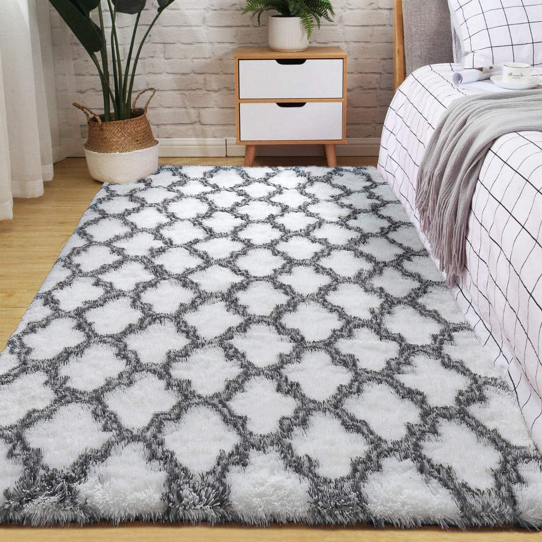 VibeCore Plush Patterned Area Rug in black design on a white background, placed beside the bed, showcasing its soft polyester fiber texture and non-slip backing. Adds comfort and style to your bedroom. Easy to clean and available in 5 stylish options.