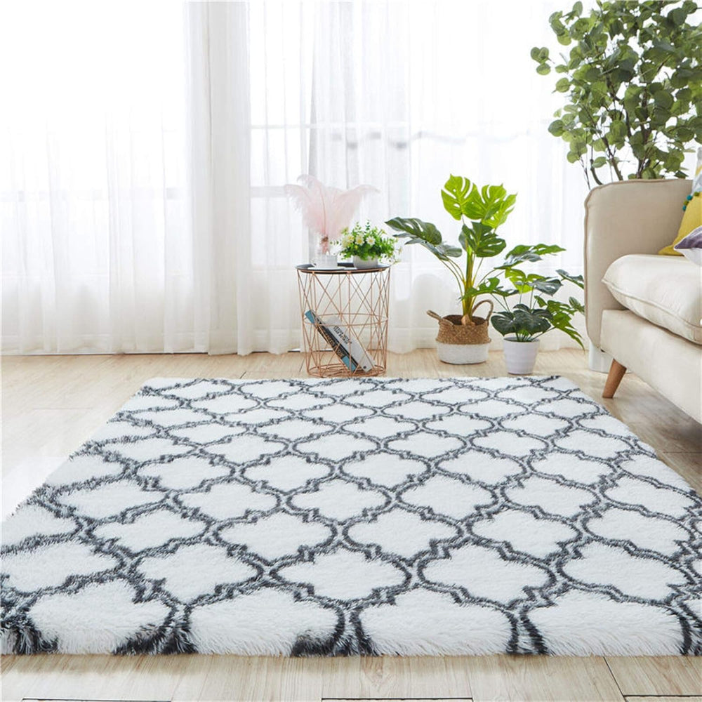 VibeCore Plush Patterned Area Rug in black design on a white background, placed in a living room, featuring a soft polyester fiber texture with non-slip backing. Adds a cozy and stylish touch to your space. Easy to clean and available in 5 stylish options.