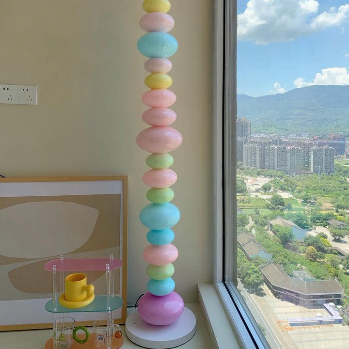 VibeCore Rainbow Candy Floor Lamp By Apartment Window – The Rainbow Candy Floor Lamp casting a vibrant glow next to a window in an apartment, bringing colorful warmth and playful vibes to the room with its eye-catching design.