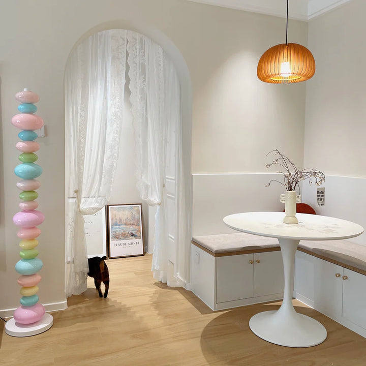The Rainbow Candy Floor Lamp standing in a vibrant dining room, casting a warm, colorful glow that complements the eclectic decor and creates a lively, inviting atmosphere.