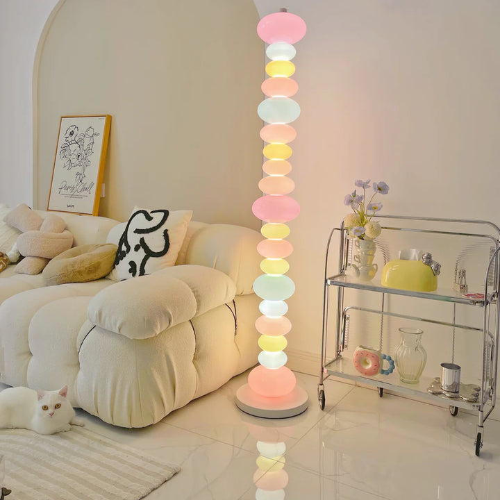 VibeCore Rainbow Candy Floor Lamp Lit In Aesthetic Living Room – Colorful, candy-inspired floor lamp illuminated in a vibrant living room setting. Featuring a sleek metal base and playful glass design, adding warmth and personality to eclectic home decor.