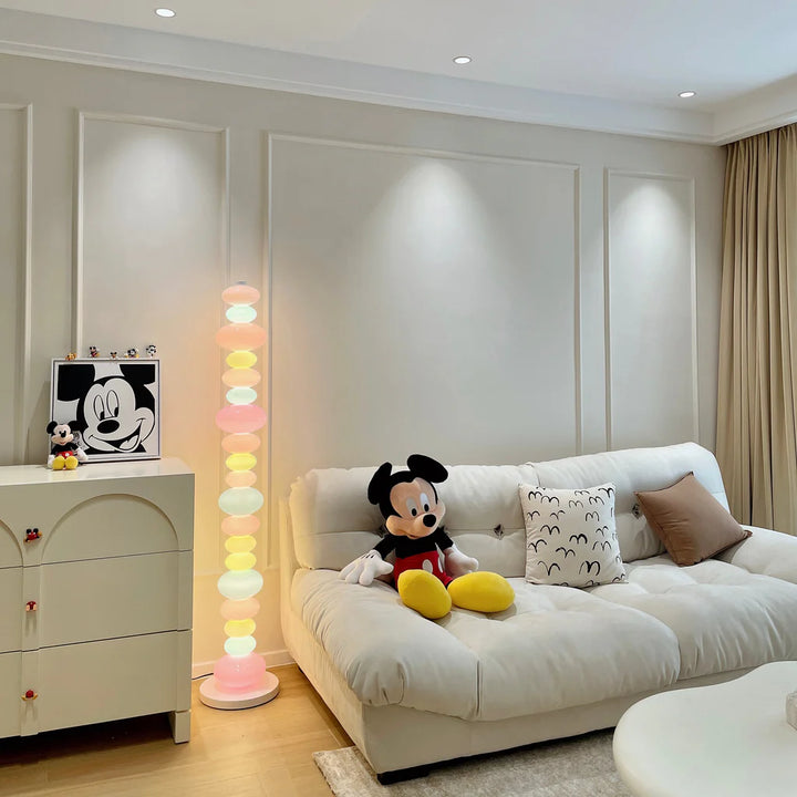 An unlit Rainbow Candy Floor Lamp positioned beside the couch, highlighting its colorful glass design and metal base, bringing a stylish, playful touch to the living room while waiting to shine.