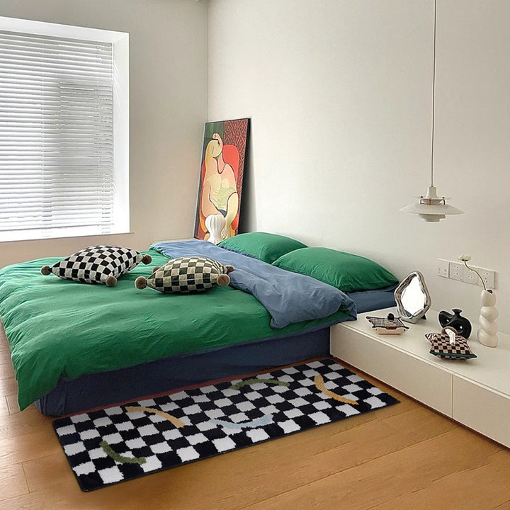 The VibeCore Retro Remix Accent Rug with a squiggle design, placed beside a bed. The bold checkered and squiggly pattern adds a playful, retro touch to the room, enhancing the modern aesthetic with its vibrant colors and plush texture.