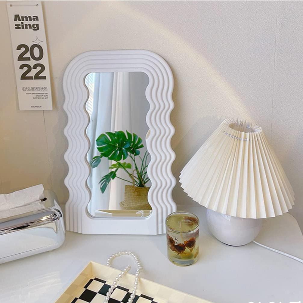 VibeCore Retro Wave Mirror in white, placed on a desk, showcasing its wave-shaped resin frame and sleek mirror lens, adding a fun and eclectic touch to the room decor.