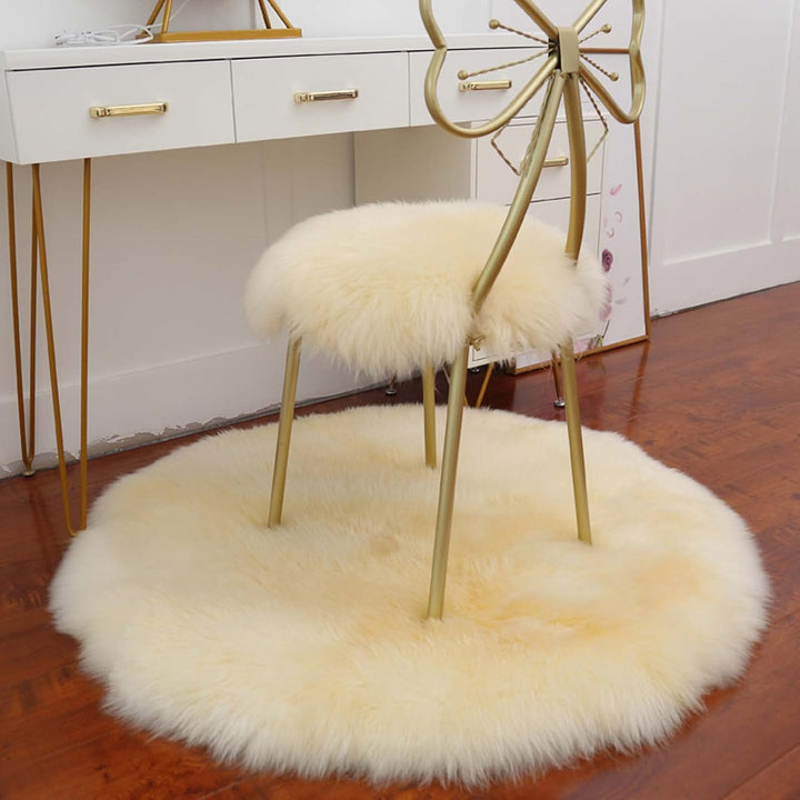 VibeCore Round Faux Fur Accent Rug in beige on the floor, also used as a seat cover. Soft, fluffy texture with a non-slip backing, perfect for bedrooms, living rooms, or dorm rooms. Easy to clean, available in multiple colors.