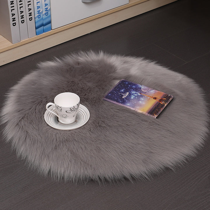 VibeCore Round Faux Fur Accent Rug in gray on the floor. Soft, fluffy texture with a non-slip backing, ideal for adding comfort to bedrooms, living rooms, or dorm rooms. Easy to clean, available in multiple colors.
