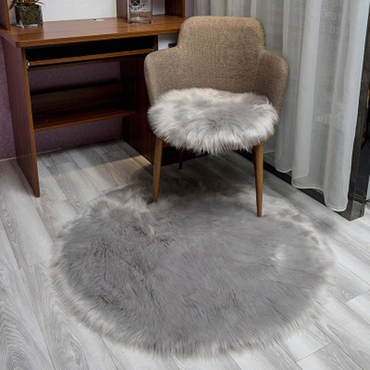 VibeCore Round Faux Fur Accent Rug in gray on the floor, also used as a seat cover. Soft, fluffy texture with a non-slip backing, perfect for bedrooms, living rooms, or dorm rooms. Easy to clean, available in multiple colors.