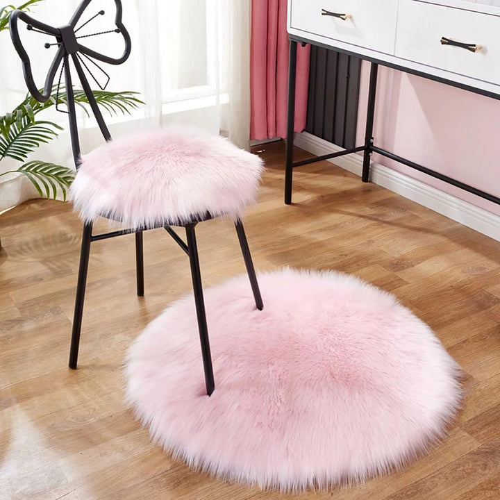 VibeCore Round Faux Fur Accent Rug in light pink on the floor, also used as a seat cover. Soft and fluffy with a non-slip backing, perfect for dorm rooms, bedrooms, or living rooms. Easy to clean, available in multiple colors.