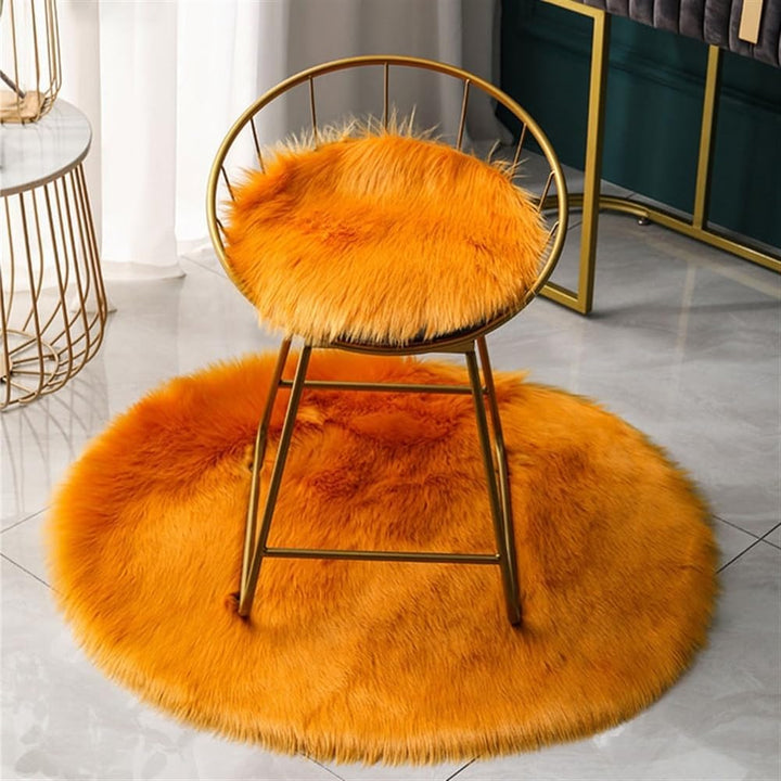 VibeCore Round Faux Fur Accent Rug in orange on the floor, also used as a seat cover. Soft, fluffy texture with a non-slip backing, perfect for bedrooms, living rooms, or dorm rooms. Easy to clean, available in multiple colors.