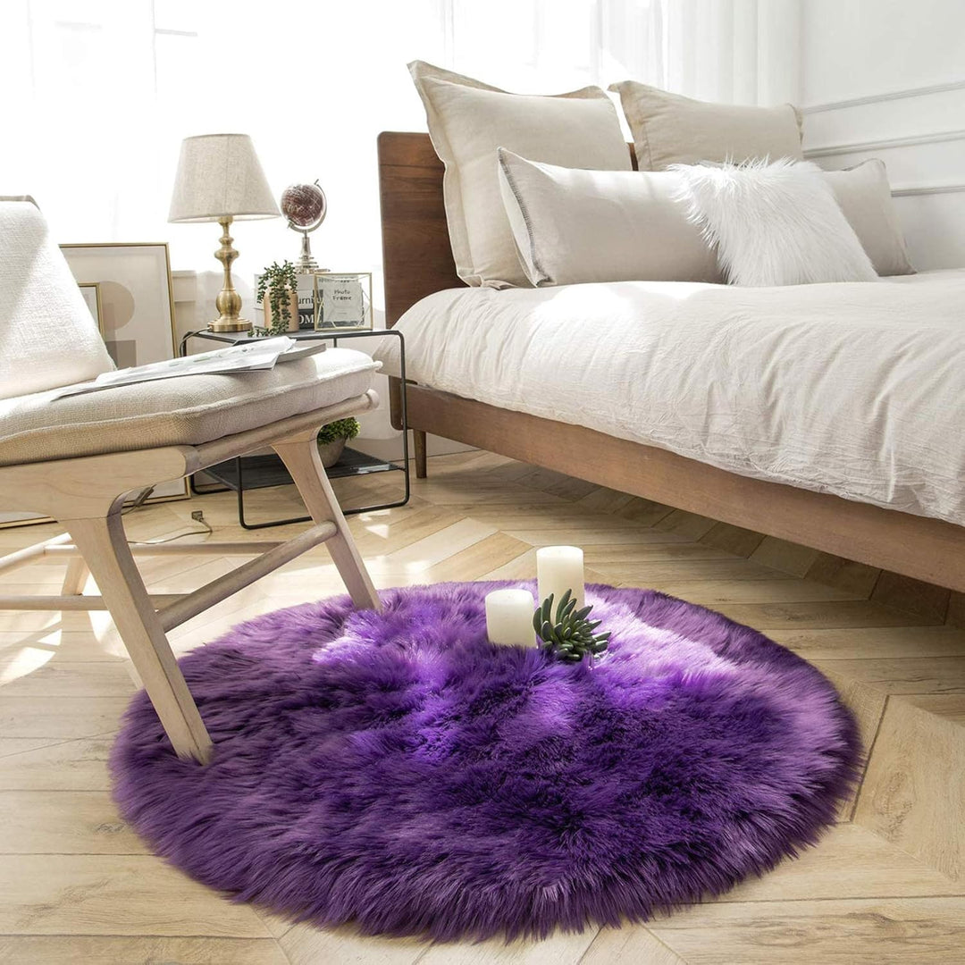 VibeCore Round Faux Fur Accent Rug in purple placed beside a bed. Soft and fluffy with a non-slip backing, ideal for adding comfort to bedrooms or dorm rooms. Easy to clean, available in multiple colors.