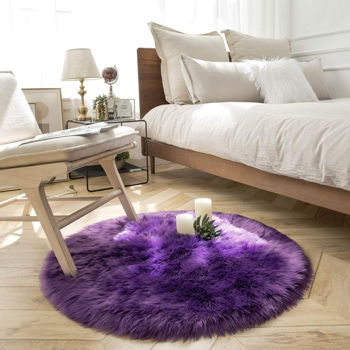 VibeCore Round Faux Fur Accent Rug in purple placed beside a bed. Soft and fluffy with a non-slip backing, ideal for adding comfort to bedrooms or dorm rooms. Easy to clean, available in multiple colors.