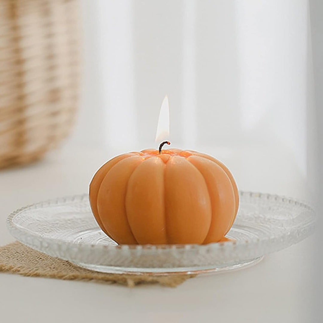 Orange scented pumpkin candle lit, filling the room with a warm, inviting fragrance, perfect for adding a cozy, autumnal touch to your decor.