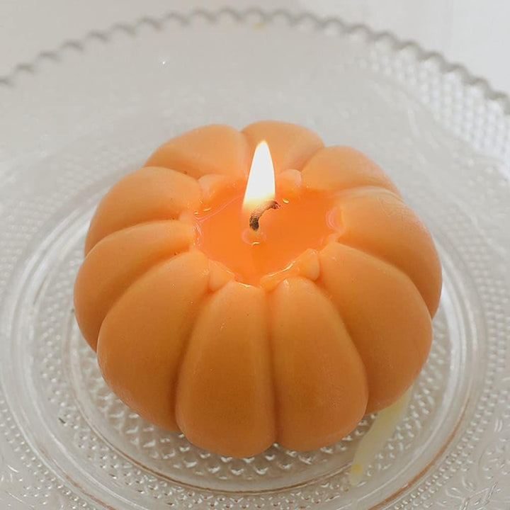 Aerial view of an orange scented pumpkin candle lit, casting a warm, inviting glow, perfect for adding a cozy, autumnal ambiance to your room decor.