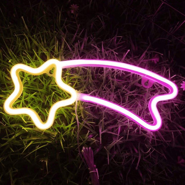 VibeCore Shooting Star Neon Light in pink and yellow, resting on the ground, casting a soft, glowing light and adding a magical, celestial touch to the room.