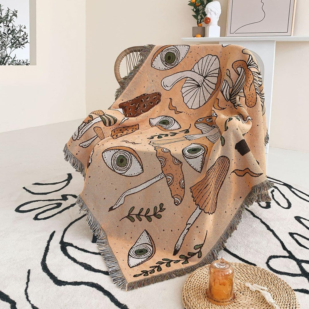 VibeCore Shroom Magic Woven Blanket draped effortlessly over a chair, showing off its playful mushroom pattern and cozy texture—an easy way to add charm and comfort to any corner.