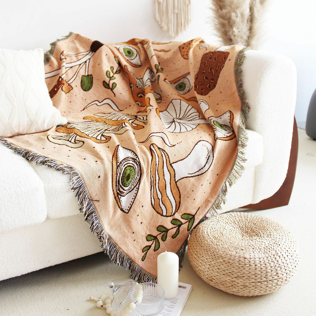 VibeCore Shroom Magic Woven Blanket draped over a couch, showcasing its whimsical mushroom design and soft woven texture.