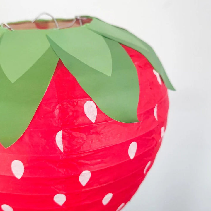Close-up view of the VibeCore Strawberry Paper Lantern Pendant, showcasing the detailed strawberry design and printed leaves, highlighting its cute and playful aesthetic.