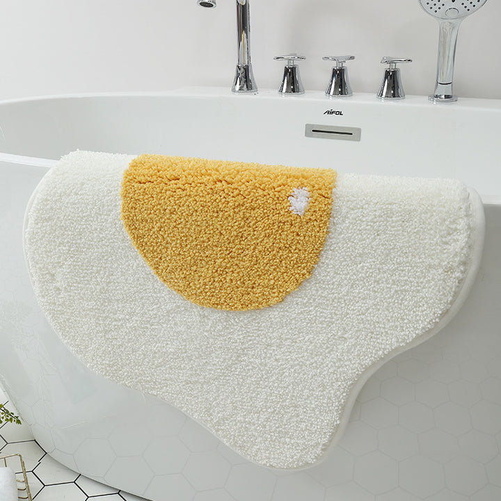 VibeCore Sunny-Side Up Egg Accent Rug strung on a tub, highlighting its playful fried egg design, soft plush texture, and non-slip backing. A cute rug that adds a quirky touch to any space, perfect for modern bedroom, dorm, or living room decor.