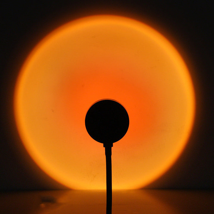 VibeCore Sunset Lamp with a deep orange center and light orange exterior casting a vibrant, warm glow in a room.