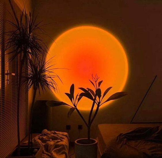 VibeCore Sunset Lamp with a deep orange center and light orange exterior projecting a warm, cozy glow on a living room wall.