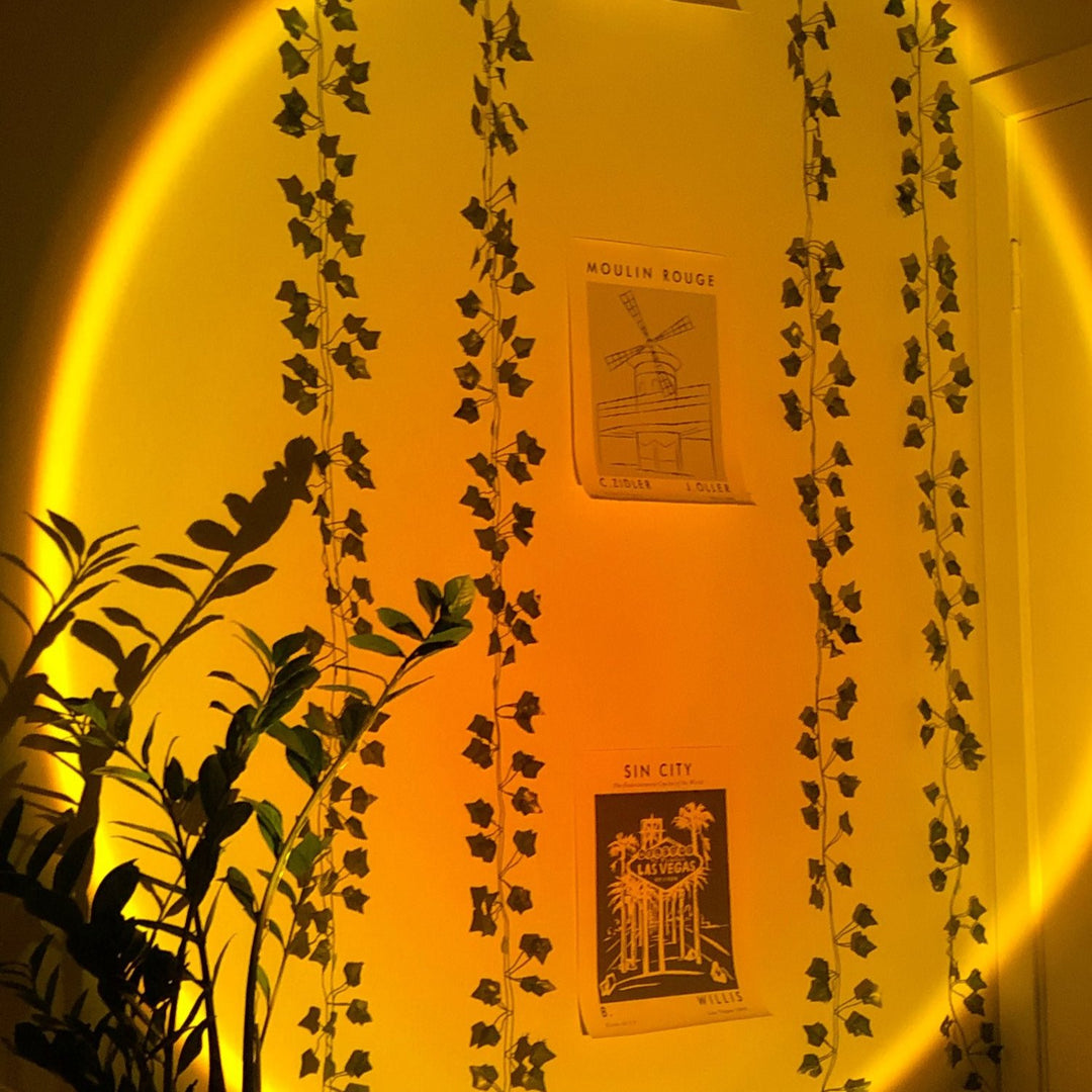 VibeCore Sunset Lamp casting a warm orange glow on a bedroom wall, creating a cozy and aesthetic ambiance, perfect for mood lighting and room decor.