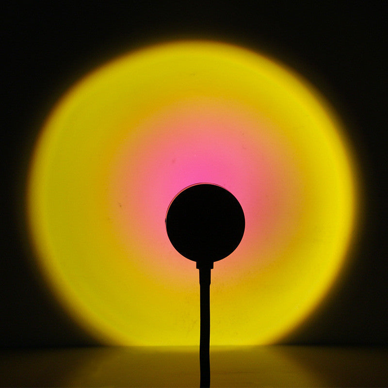 VibeCore Sunset Lamp with a pink interior and yellow exterior, projecting a warm, vibrant glow on the wall, adding a cheerful and inviting atmosphere to the room.