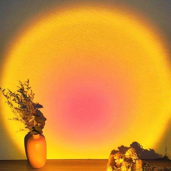 VibeCore Sunset Lamp with a pink interior and yellow exterior projecting a vibrant glow on the wall, creating a warm and inviting atmosphere in the room.