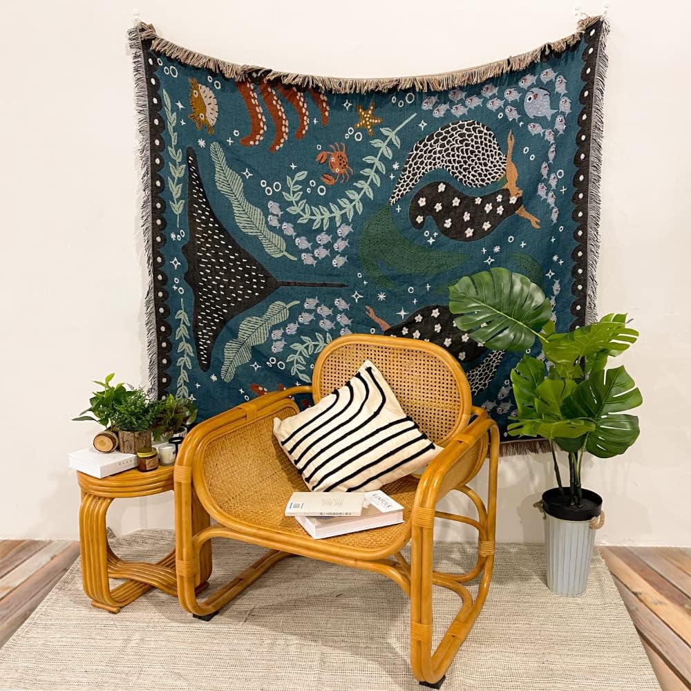 VibeCore Swimming Mermaids Woven Blanket as a wall hanging, showcasing an enchanting mermaid design and soft 100% combed cotton texture.