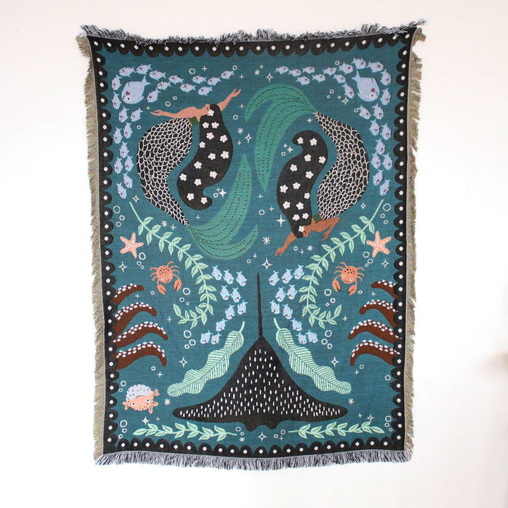 VibeCore Swimming Mermaids Woven Blanket product view, featuring an enchanting mermaid design and soft 100% combed cotton texture.