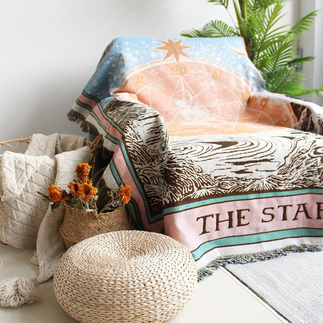VibeCore The Star Tarot Woven Blanket draped over a chair, showcasing its celestial-inspired design and reversible patterns with vibrant colors and soft cotton texture.