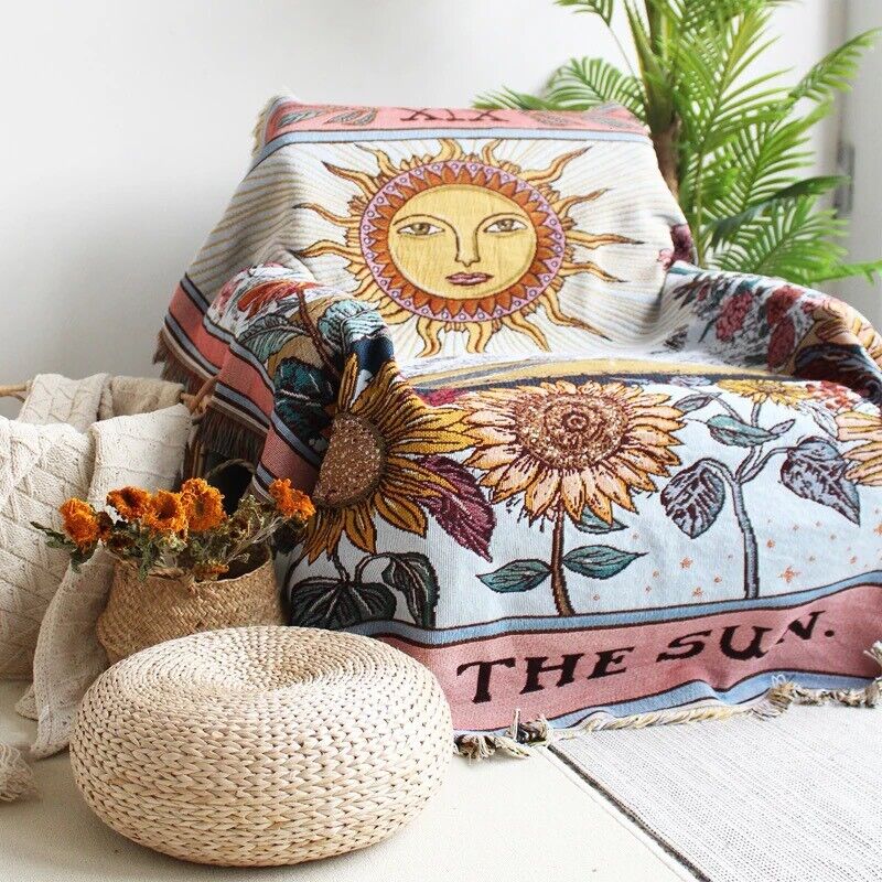 VibeCore The Sun Tarot Woven Blanket draped on chair, featuring a celestial-inspired design with vibrant patterns. Made from soft, breathable 100% combed cotton, it adds a cosmic, artistic touch while offering versatility as a throw, wall hanging, or stylish rug.