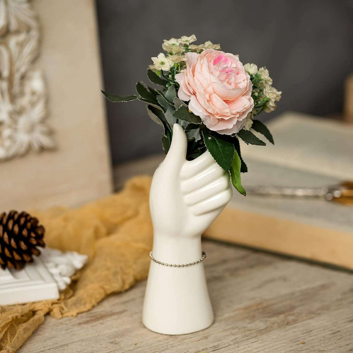 A hand-shaped ceramic vase filled with vibrant flowers, highlighting its unique design and glazed porcelain finish, adding a stylish and modern touch to any room.