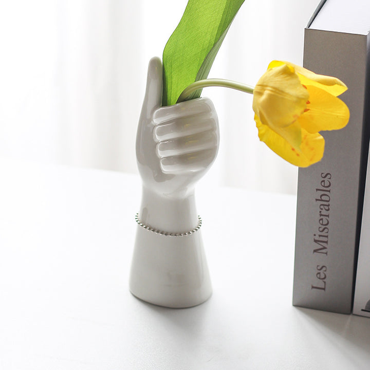 Hand-shaped ceramic vase holding fresh flowers, displayed on a table for a bold, artistic decor accent.