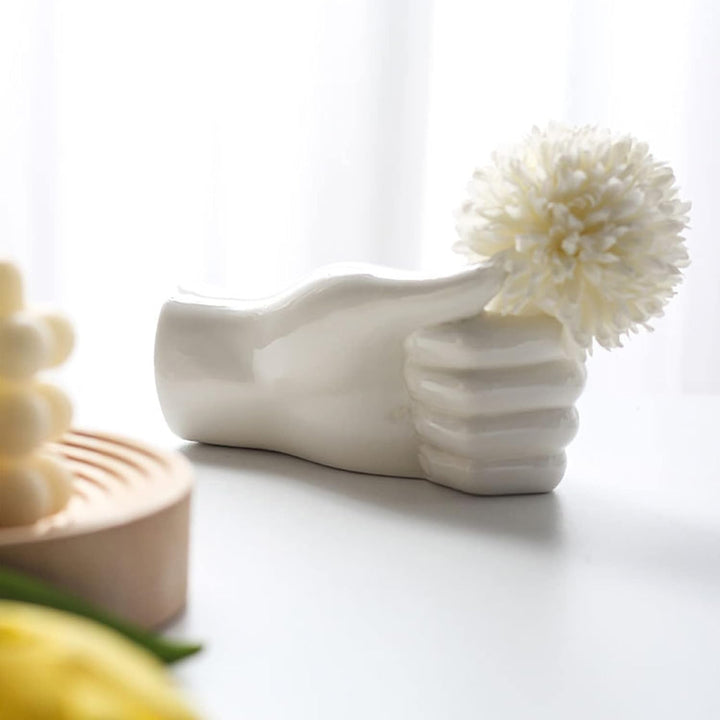 Unique thumbs-up shaped ceramic vase styled with a single flower, adding playful elegance to modern decor.