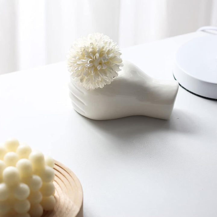 Playful thumbs-up ceramic vase with flower, styled on a table for modern artistic home decor.