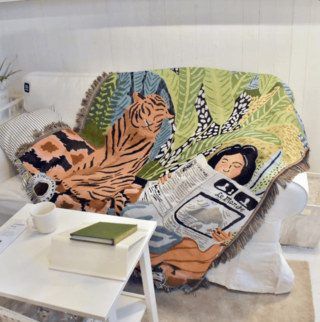 Tiger Lounge Woven Blanket draped over a couch, featuring its bold, artistic-inspired design and 100% combed cotton for ultimate softness. Reversible for two striking looks, adding vibrant style and versatility to any space.