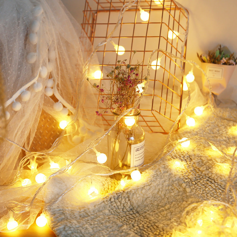 Close-up of VibeCore tiny ball string lights, glowing with a soft, warm white light.