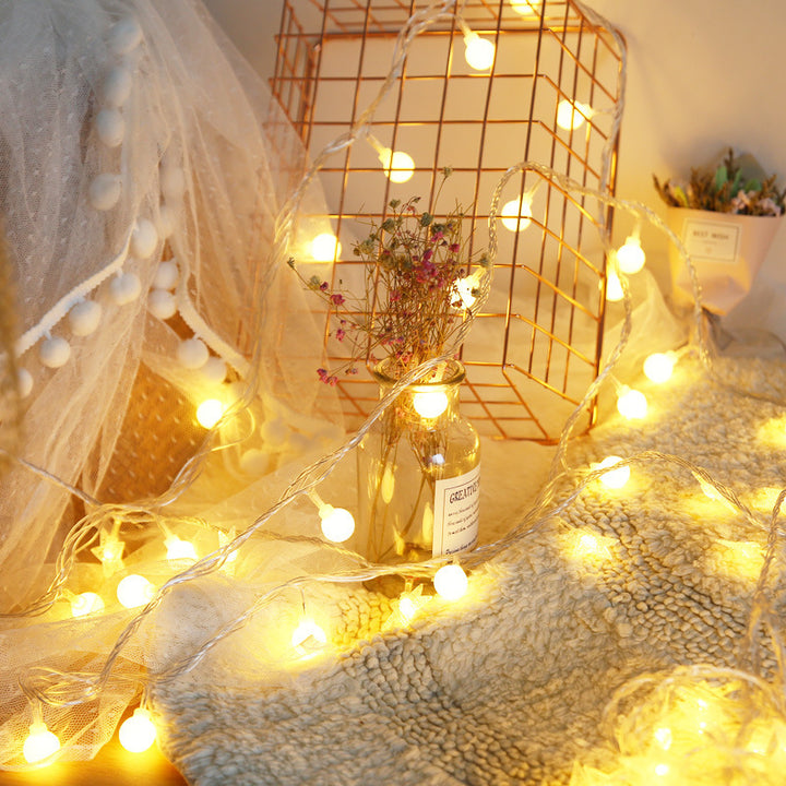 Close-up of VibeCore tiny ball string lights, glowing with a soft, warm white light.